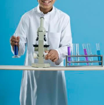 School boy using a microscope with chemicals in test tubes Stock Photos