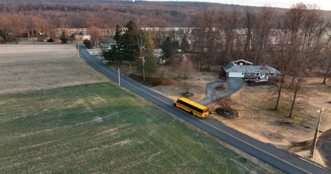 School bus drives on road through rural American countryside. Homes at Stock Footage 171955739