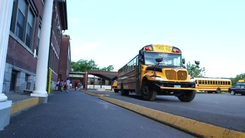 School buses parked outside of Sprague Elementary school, kids walking Stock Footage 304367540