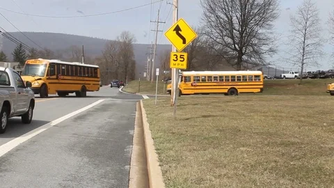 School buses pulling out of school onto road Stock Footage 73881536