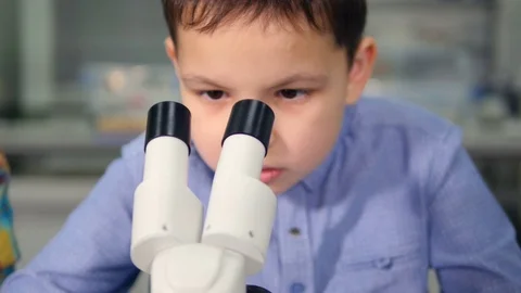 School child looking into microscope doing a science experiment in chemistry Stock Footage 73907247