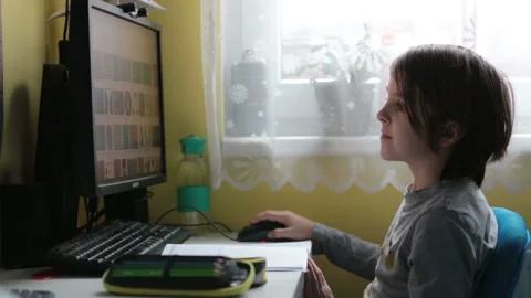 School child, sitting at the table with laptop, writing school tasks while ho Stock Footage 146890537