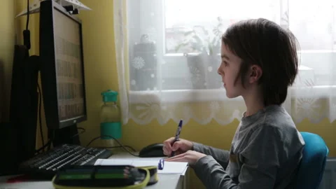 School child, sitting at the table with laptop, writing school tasks while ho Stock Footage 146890544