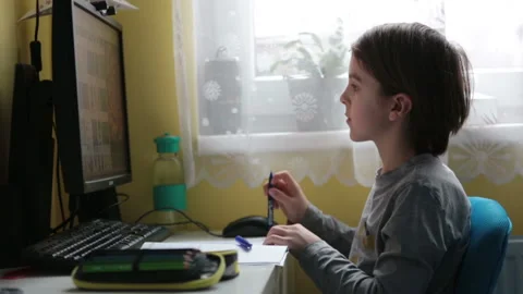 School child, sitting at the table with laptop, writing school tasks while ho Stock Footage 146890569