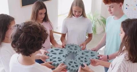 School children group connecting big gears together finding solution standing in Stock Footage 318353663