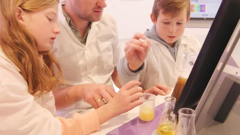 School children making experiments using test tubes with teacher in laboratory Stock Footage 236363682