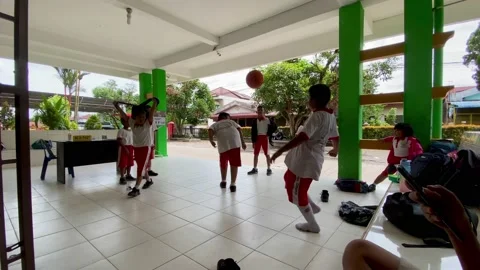 School children play ball while waiting to be picked up by their parents Stock Footage 234579443