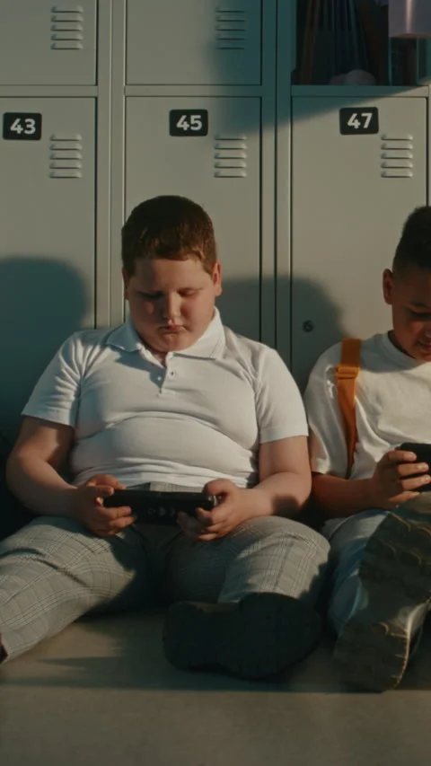 School Children Relax by Lockers While Sharing Content on Portable Devices Stock Footage 342033765