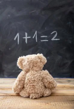 School class math. Teddy bear looking at a simple equation on a blackboard. Stock Photos
