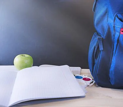 School concept, blue backpack with pencils on the table in front of the chalk Stock Photos