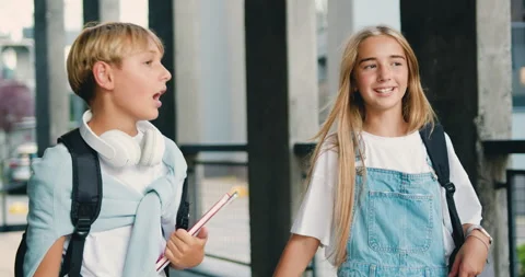 School couple. Friendly children with backpacks walking on stairs near school Stock Footage 248613623