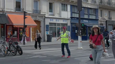 A school crossing guard in a high visibility vest protects street pedestrians Stock Footage 336721851