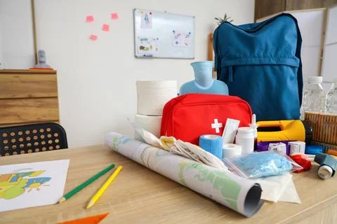 School desk with emergency backpack and necessities in classroom, closeup Stock Photos