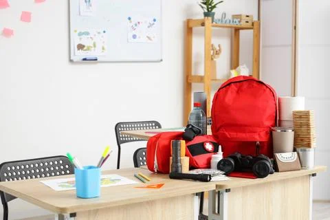 School desk with emergency backpack, binoculars and necessities in classroom Stock Photos