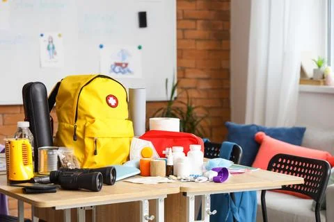 School desks with emergency backpack, binoculars and necessities in classroom Stock Photos