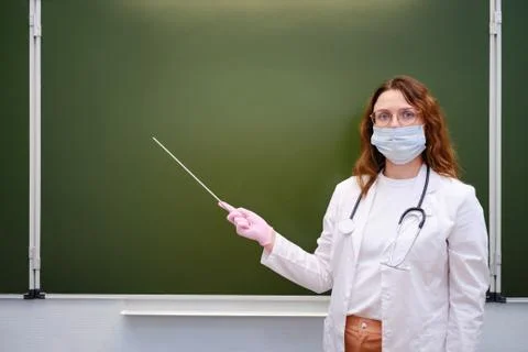 School doctor shows a pointer to a blank chalkboard, copy space Stock Photos