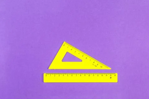 School drawing tools. Yellow triangle and ruler on a purple background Stock Photos