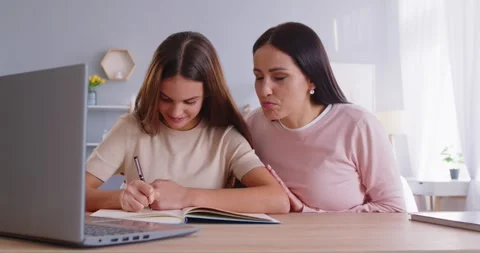 School girl doing homework and studying online at home with mother helping her Stock Footage 331148647