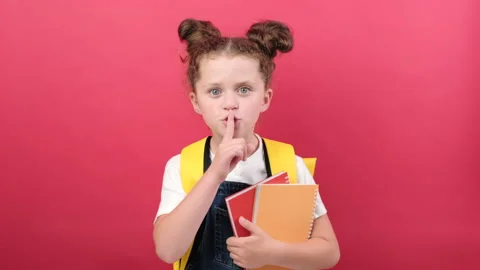 School girl hold books secret say hush be quiet, finger on lips shhh gesture Stock Footage