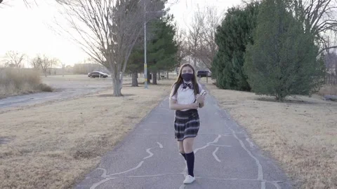 School girl skips down path through park area, happy and care smiling at camera. Video stock 168490283