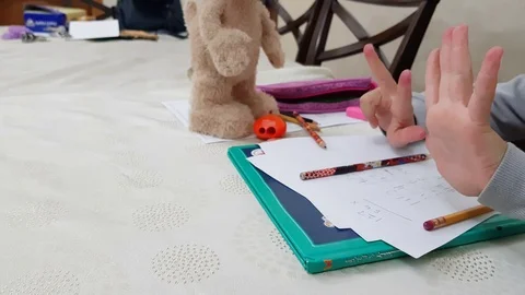 School girl trying to solve math homework by hand counting Stock Footage 98566691