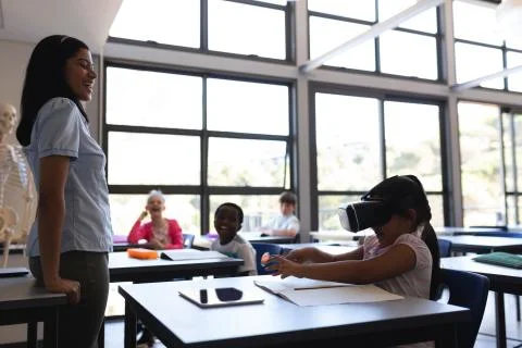 School girl using virtual reality headset at desk in classroom Stock Photos