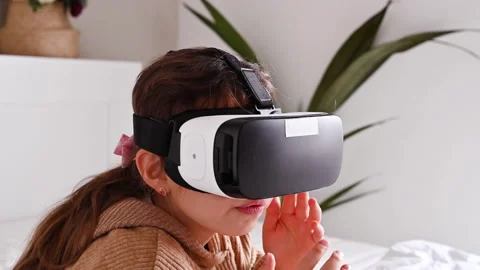 School girl using VR glasses and exploring virtual worlds. Little girl wearing v Stockbeeldmateriaal 143572072