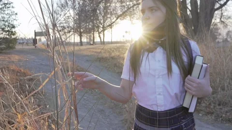 School girl walks down path through woods with sunshine behind her. Video stock 168490287