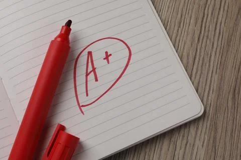 School grade. Red letter A with plus symbol on notebook paper and marker on.. Stock Photos