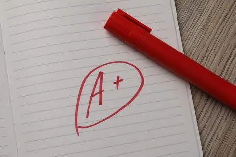 School grade. Red letter A with plus symbol on notebook paper and marker on.. Stock Photos
