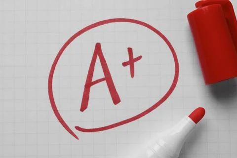 School grade. Red letter A with plus symbol on notebook paper and marker, t.. Stock Photos