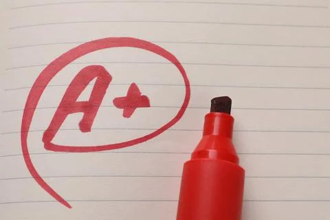 School grade. Red letter A with plus symbol on notebook paper and marker, t.. Stock Photos