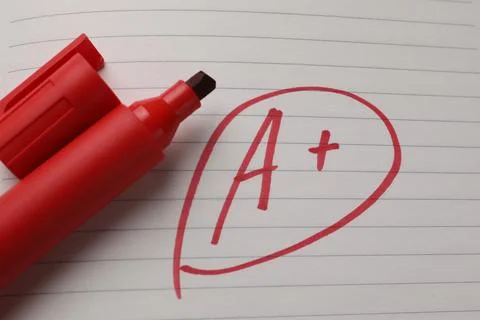 School grade. Red letter A with plus symbol on notebook paper and marker, t.. Stock Photos