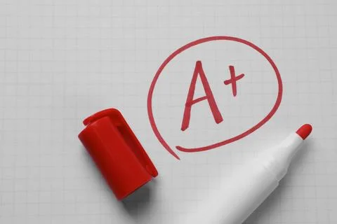 School grade. Red letter A with plus symbol on notebook paper and marker, t.. Stock Photos
