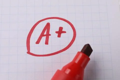 School grade. Red letter A with plus symbol on notebook paper and marker, t.. Stock Photos