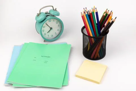 School items. Alarm clock, notebooks, pencils for drawing on a white backgrou Stock Photos