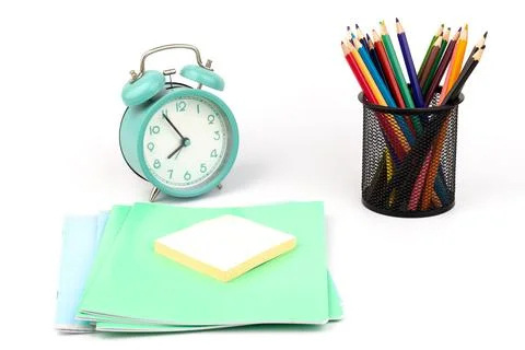 School items. Alarm clock, notebooks, pencils for drawing on a white backgrou Stock Photos