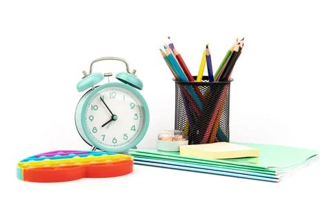 School items. Alarm clock, notebooks, pencils for drawing and silicone toy po Stock Photos