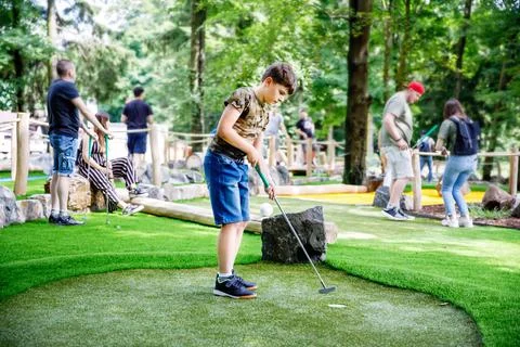 School kid boy playing mini golf with family. Happy child having fun with 스톡 사진