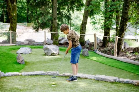 School kid boy playing mini golf with family. Happy child having fun with 스톡 사진