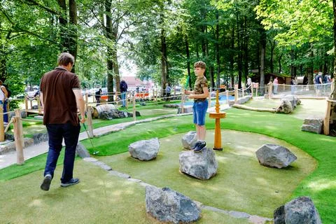 School kid boy playing mini golf with father. Happy child and dad, young man Stock-Fotos