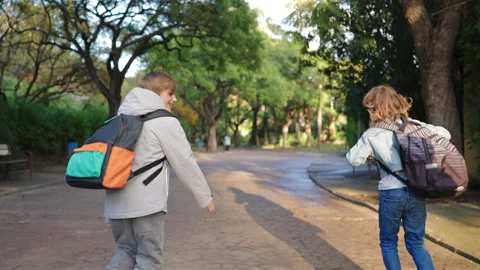 School kids with backpacks running through sunny park path on way to school. Stock Footage 338140877