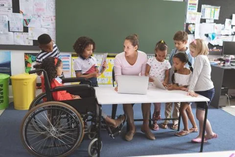 School kids using digital tablet while teacher interacting with students at Stock Photos