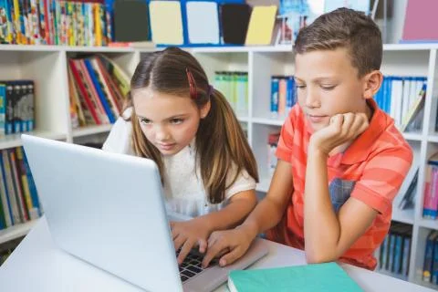School kids using a laptop in library at school Stock Photos