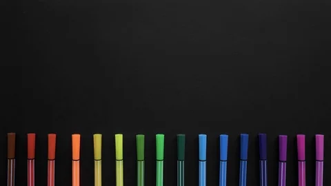 School markers of different colors are located on the black surface. Stop motion Vidéo 108475304