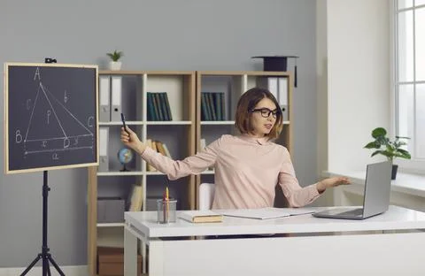 School math teacher sitting at desk with laptop and giving online geometry Stock Photos