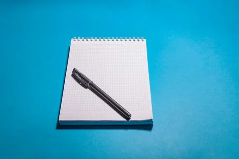 School notebook in a cage for notes with a ballpoint pen on a blue background Stock Photos