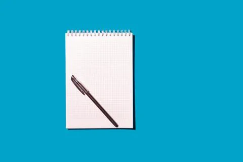 School notebook in a cage for notes with a ballpoint pen on a blue background Stock Photos
