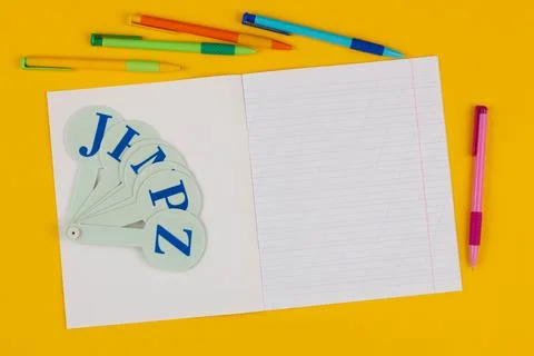 School notebook on a yellow background with copy space for text, colorful pens Stock Photos