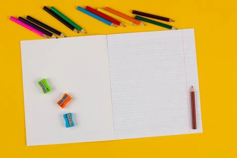 School notebook on a yellow background with copy space text, colorful pencils Stock Photos